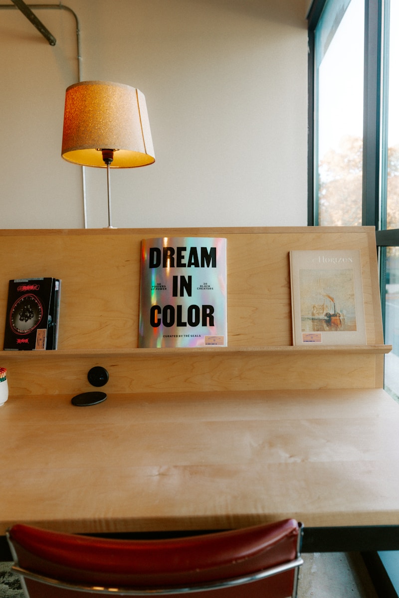 Shelf with books and artwork above a wooden desk.