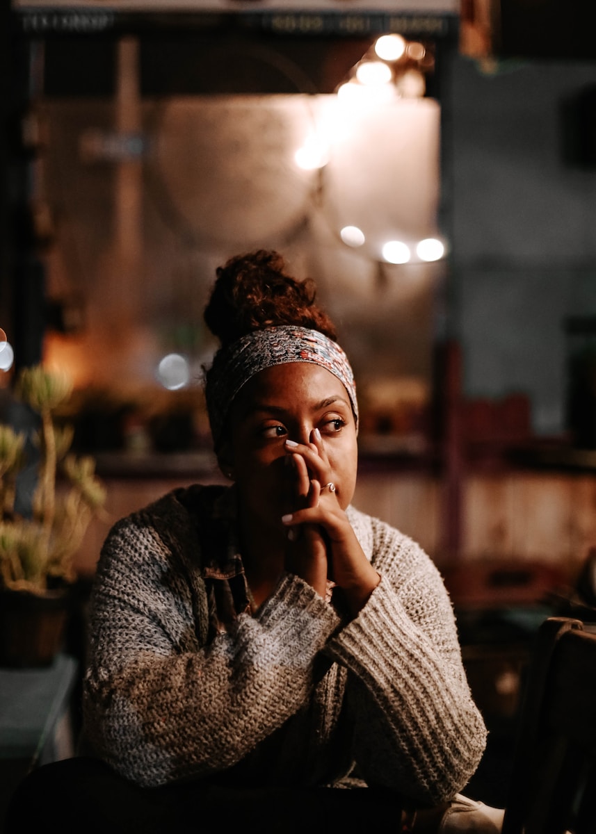 woman in sweater sitting on chair overthinking